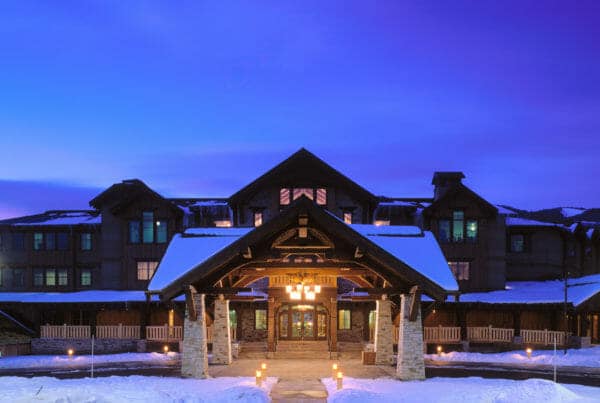 Hotel Park City exterior with snow on roof lights up during twilight - architecture by Think